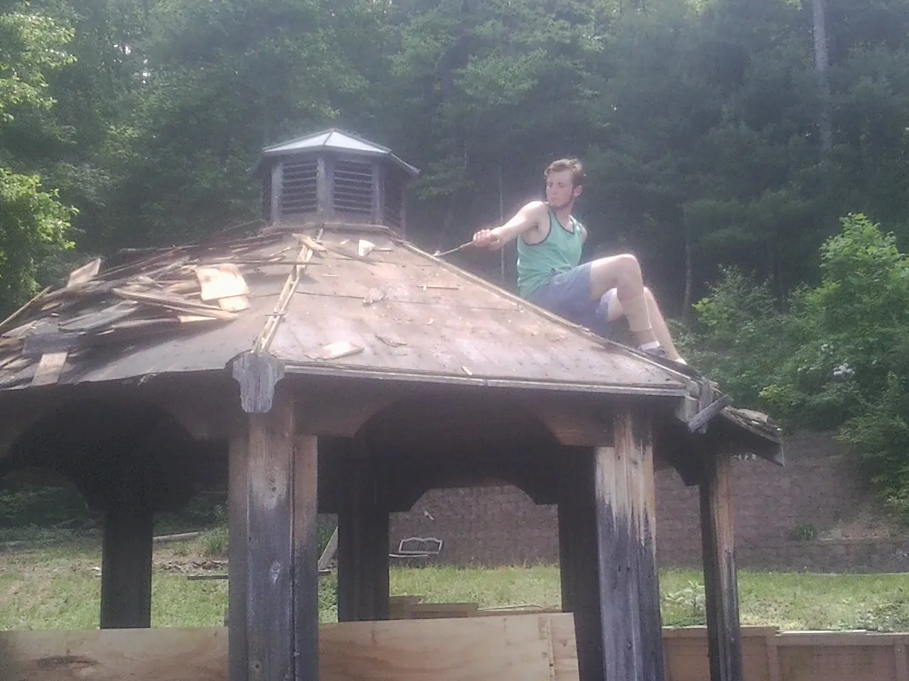 Tearing the old roof off a wooden gazebo before new shakes in Alma