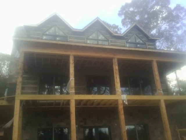 Dormers and porch framing on a large log home under construction — Roof Coating work by our crew in Alma